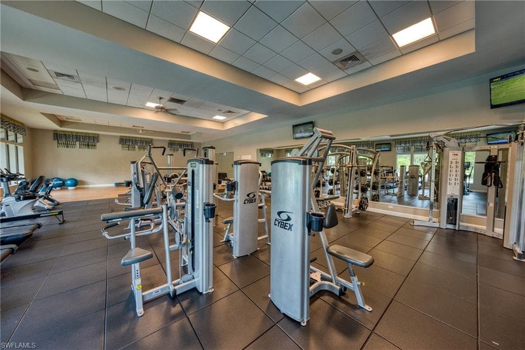 Fitness center featuring extensive weight training equipment, cardio machines, rubberized flooring, and multiple ceiling-mounted televisions