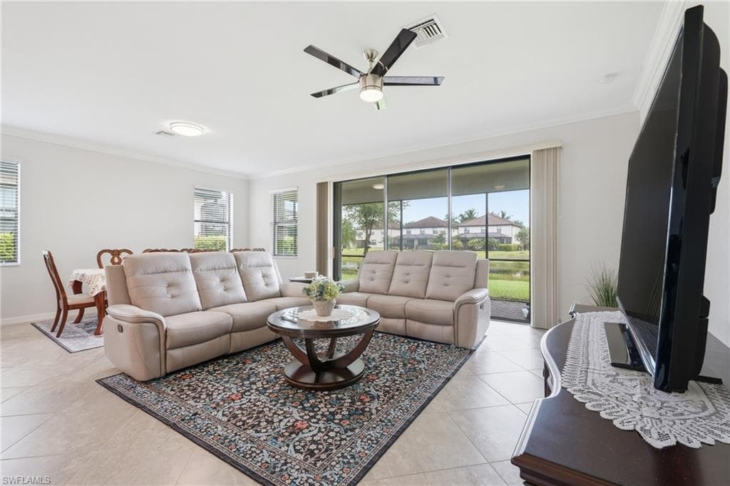 Spacious living area featuring light tile flooring and a ceiling fan