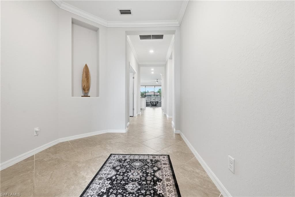 Hallway featuring light neutral walls, crown molding, a built-in display niche, tile flooring, and recessed lighting