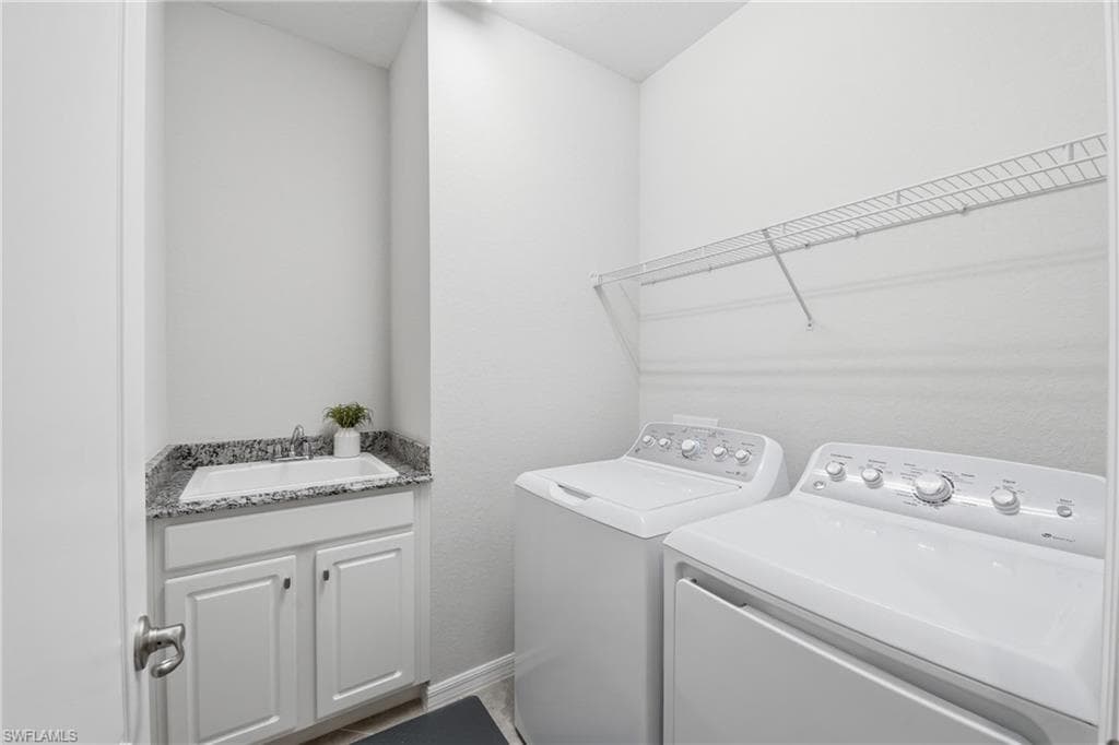 Dedicated laundry room featuring a utility sink with a granite-style countertop, white cabinetry, a wire shelving unit, and hard surface flooring