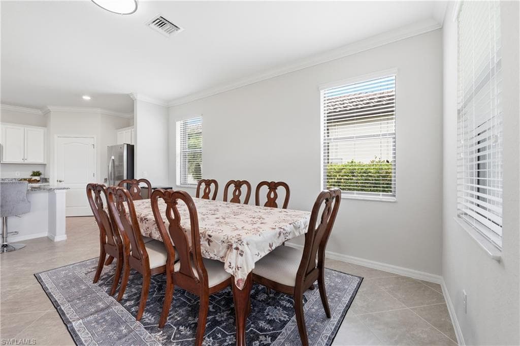 Dining area featuring tile flooring, white crown molding, and two windows with horizontal blinds