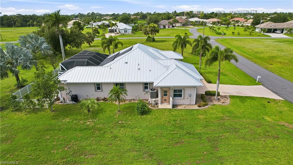 Modern metal roof residence set on expansive manicured grounds featuring mature landscaping, including palm trees and established vegetation