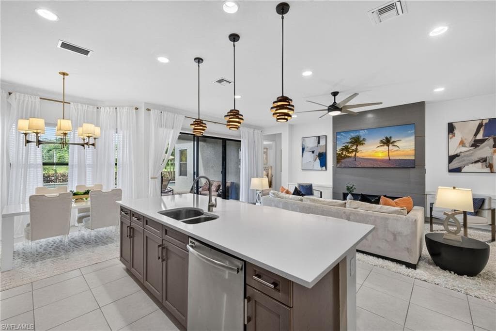 Spacious open-concept living area featuring a large kitchen island with integrated sink, stainless steel dishwasher, and recessed lighting