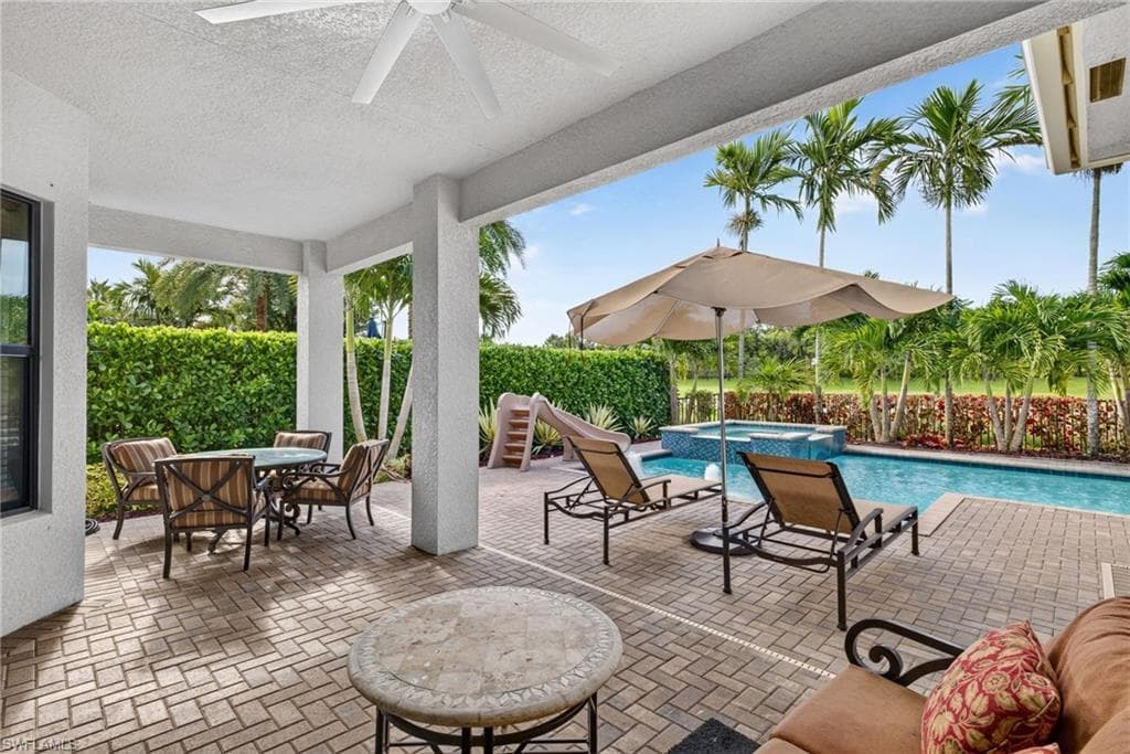 Covered patio with a ceiling fan, brick paver flooring, swimming pool, and raised spa