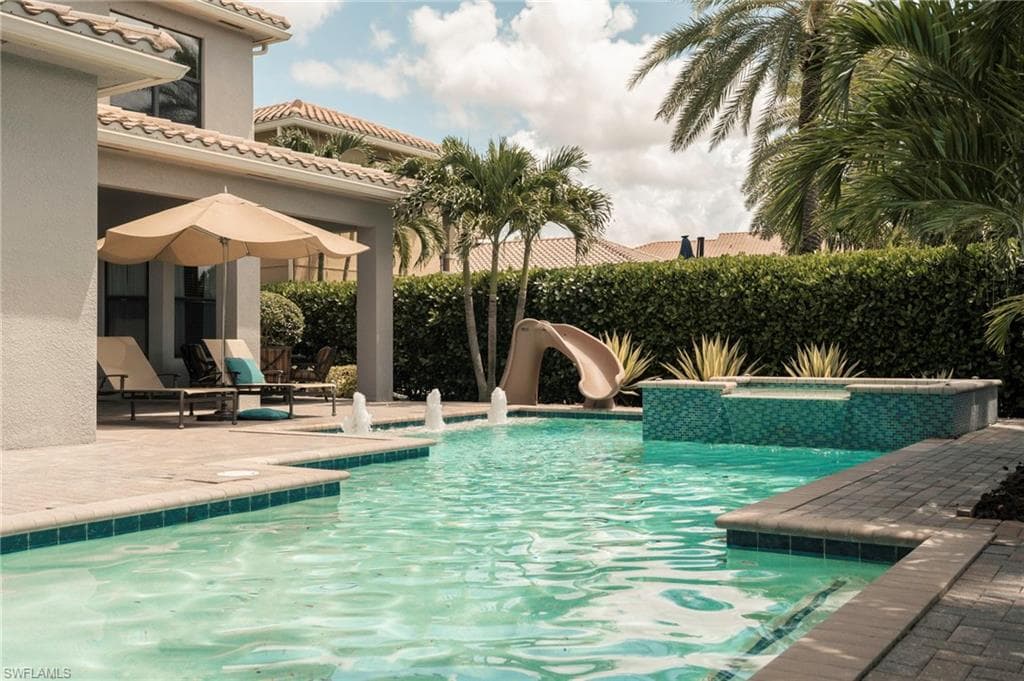 Private backyard with swimming pool, elevated spa with mosaic tile, water features, and an integrated slide