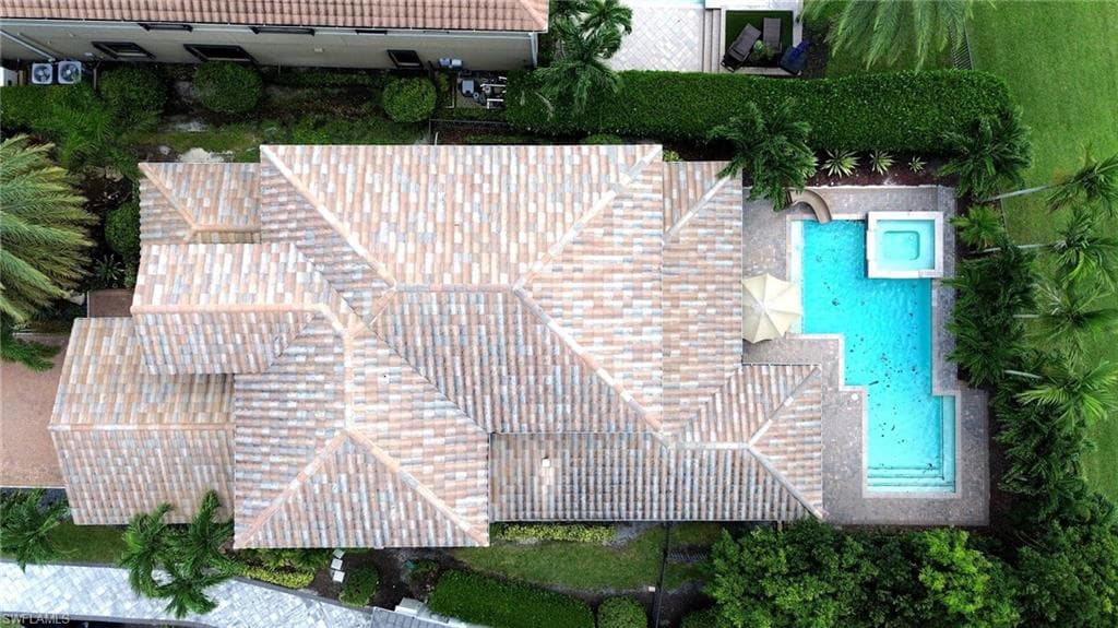 Tile roof with multiple gables, rectangular swimming pool, integrated spa, and manicured landscaping
