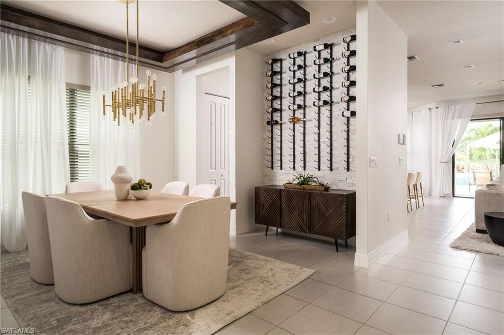Dining area featuring a textured wine wall, contemporary chandelier, wood-finish beam accents, and tile flooring