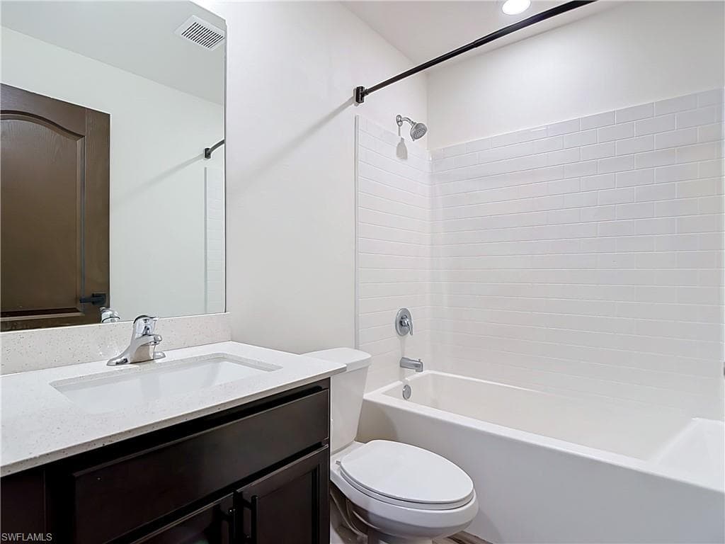 Full bathroom featuring a dark wood-finish vanity with a light-toned countertop and an integrated sink