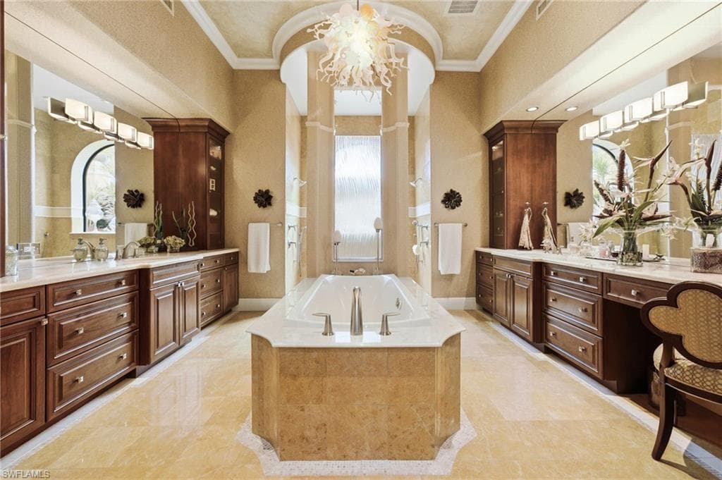 Designed for ultimate relaxation, the spa-inspired primary ensuite showcases exquisite custom wood cabinetry, elegant marble countertops, and luxurious marble flooring. Separate vanities frame a sculptural soaking tub, while an expansive walk-through shower with dual shower heads provides a truly indulgent experience. A magnificent custom chandelier crowns the space, creating an elegant finishing touch and transforming this exceptional retreat into a private spa sanctuary.