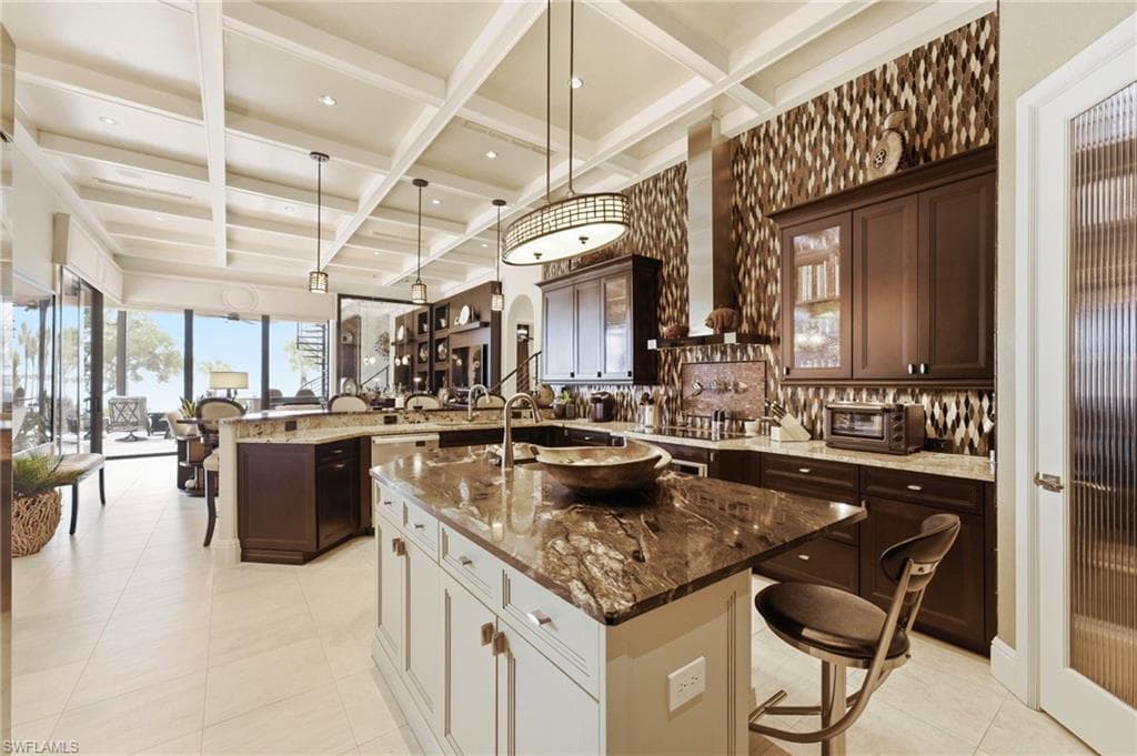 The centerpiece of this extraordinary kitchen is its magnificent marble-topped island, complemented by a beautifully appointed bar with ample seating—an inviting setting where family and friends can gather, entertain, and create unforgettable memories.