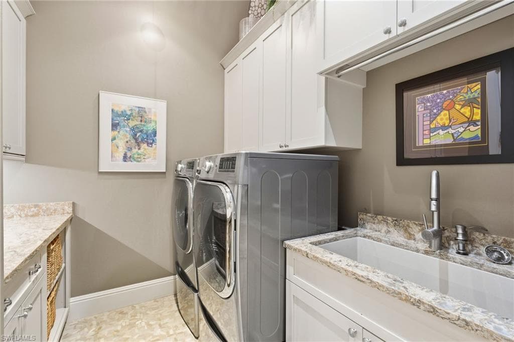 The thoughtfully appointed laundry space offers abundant storage, elegant marble countertops, sophisticated under- and overhead lighting, convenient hanging space, and a front-loading washer and dryer.