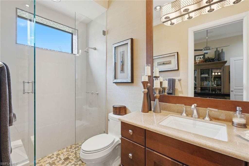 The fourth ensuite bath exudes refined elegance with luxurious marble flooring, a single marble-topped vanity, a walk-in shower with seamless glass enclosure, and sophisticated grasscloth wallpaper adding a touch of texture and warmth.