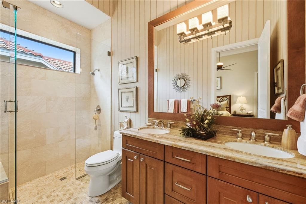 The third ensuite bath showcases luxurious marble flooring, dual Level 3 granite countertops, a walk-in shower with seamless glass enclosure, custom floor-to-ceiling tilework, and a transom window that fills the space with natural light.