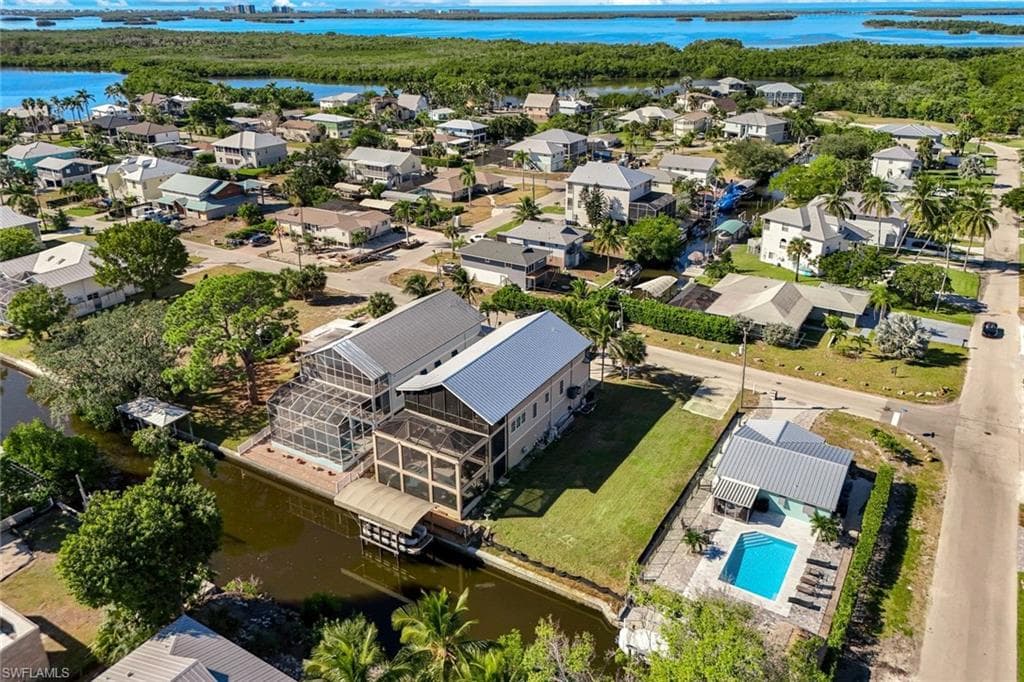 Aerial perspective of suburban area featuring a nearby body of water and a pool