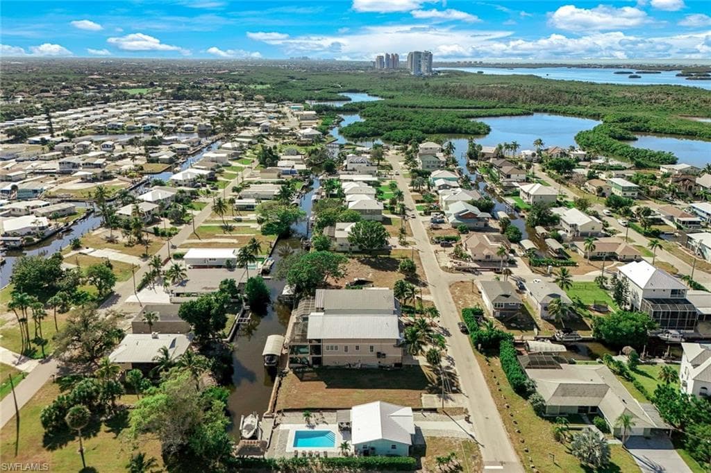 Aerial view of property and surrounding area featuring a nearby body of water and nearby suburban area
