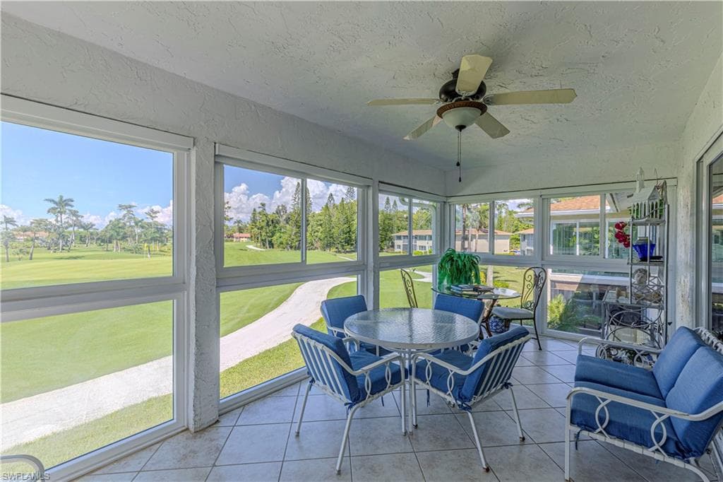 Sunroom / solarium featuring a ceiling fan, view of golf course, and plenty of natural light