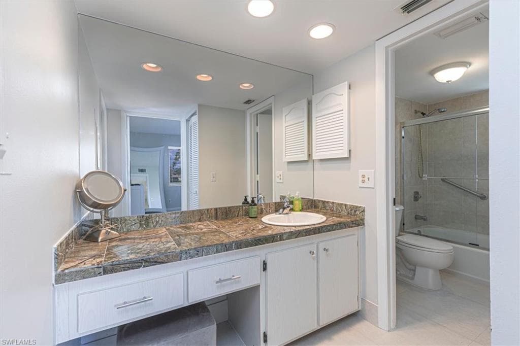 Bathroom featuring vanity, shower / bath combination with glass door, light tile patterned floors, and recessed lighting