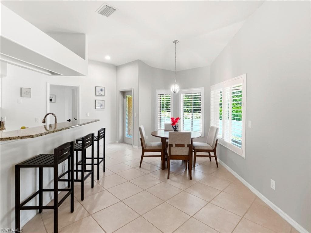 Tiled flooring, vaulted ceiling, bay window, plantation shutters, and a breakfast bar with stone-finish countertop