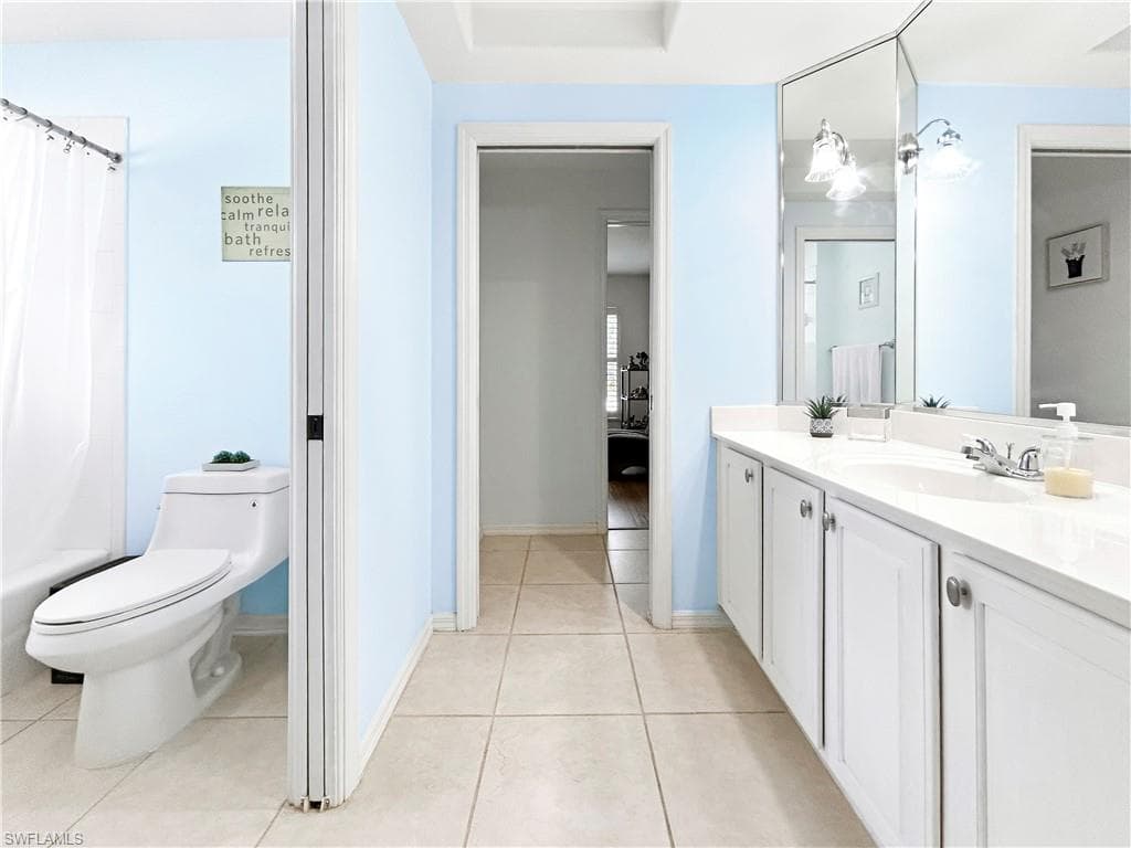 Double vanity with white cabinetry, light-toned countertop, and tile flooring