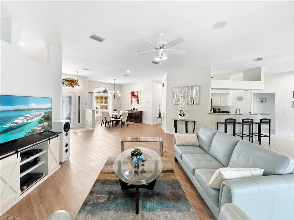 Open-concept living area with wood-finish flooring, recessed lighting, a ceiling fan, and a breakfast bar