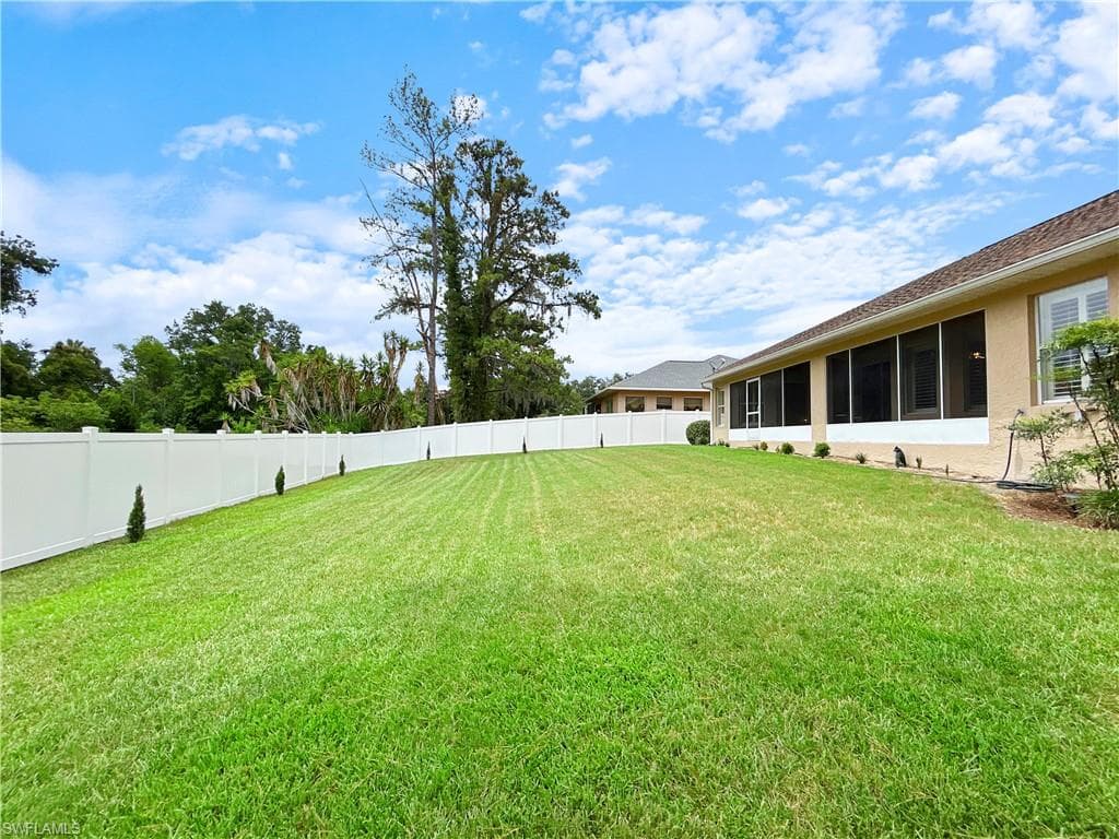 Expansive lawn area with a white privacy fence