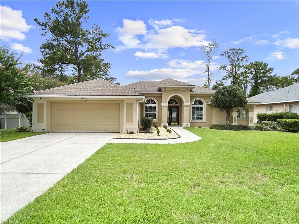 Contemporary stucco exterior with arched entry, arched windows, an attached two-car garage, and a concrete driveway