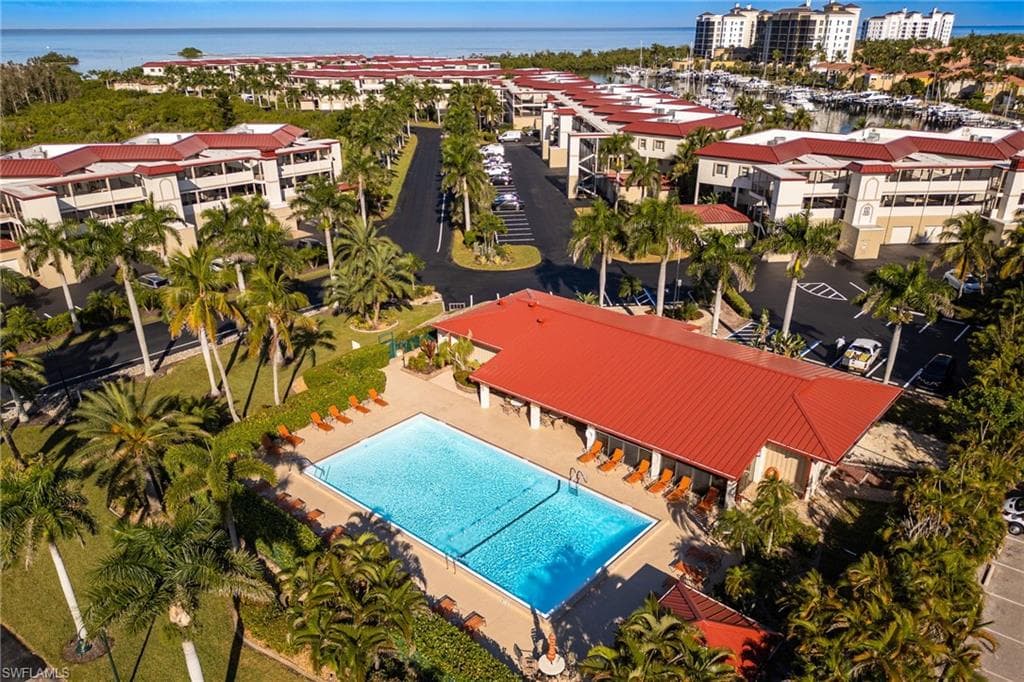 Community pool area featuring a rectangular swimming pool, surrounding lounge seating, and a covered patio structure with a red roof