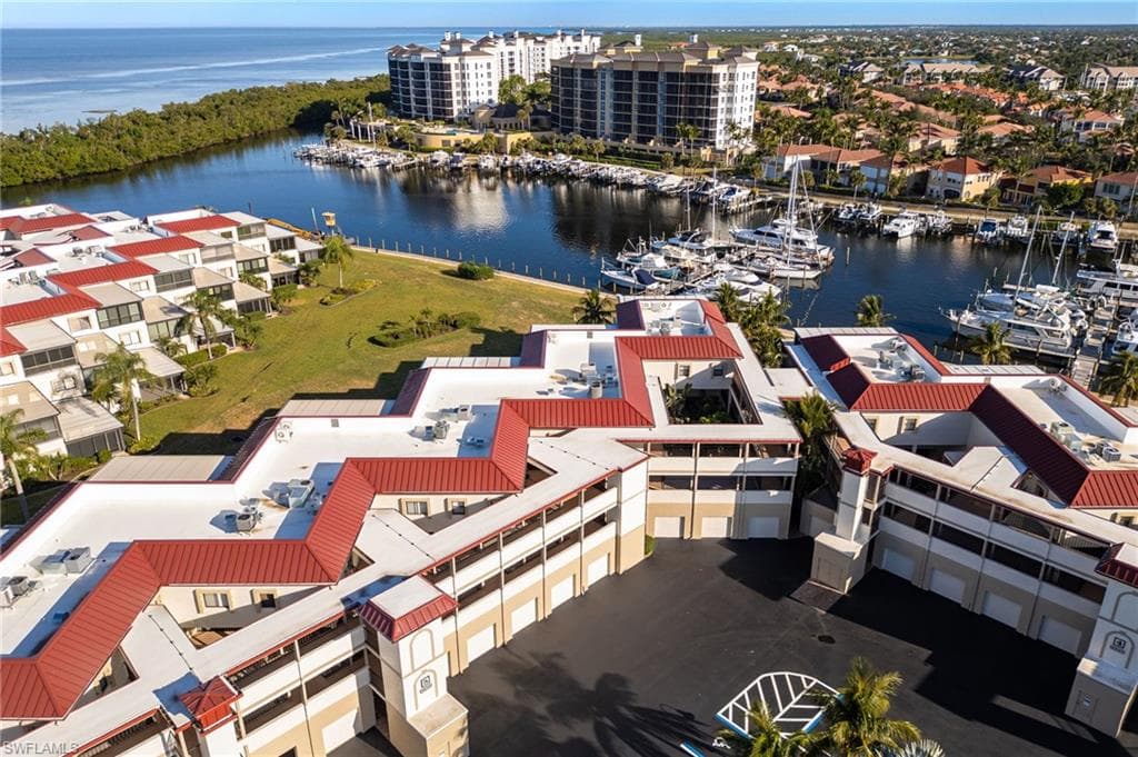Waterfront complex featuring extensive boat docks, multiple residential buildings with red tile roofs, and a paved parking area