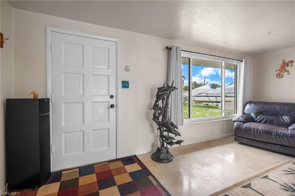 White paneled entry door, light-toned wall paint, hard-surface flooring, and sliding window with vertical blinds