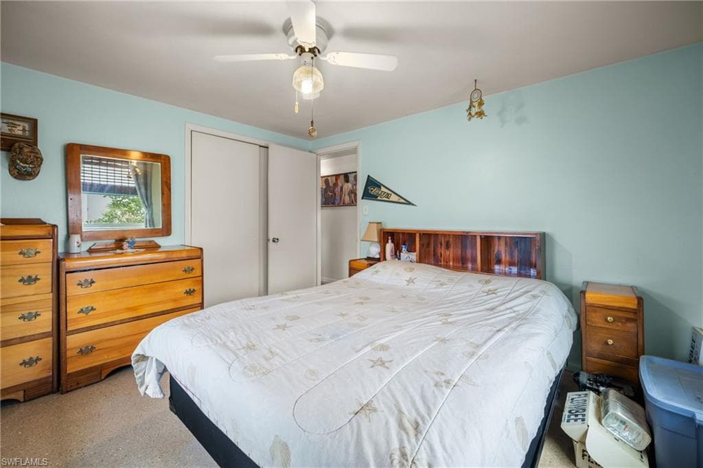 Recessed lighting, ceiling fan with light fixture, wood-finish headboard with built-in shelving, sliding closet doors, and light-toned wall paint