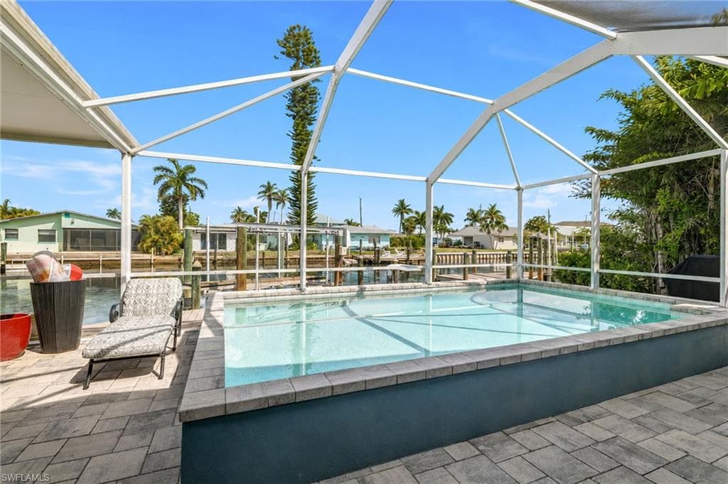 Screened enclosure featuring a rectangular pool, paver patio, and water frontage