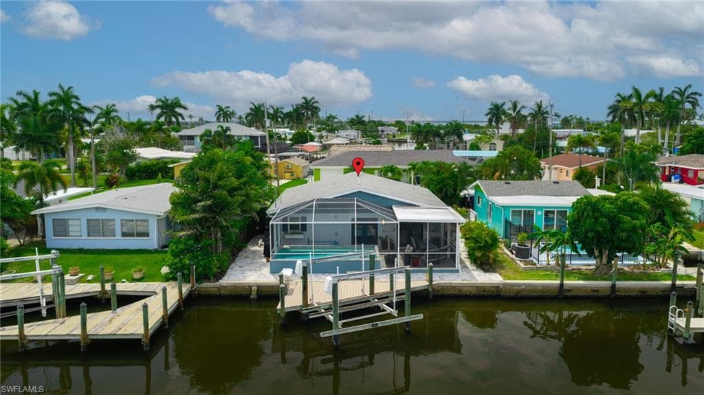 Waterfront property featuring a screened-in pool enclosure, private boat dock, and mature palm trees