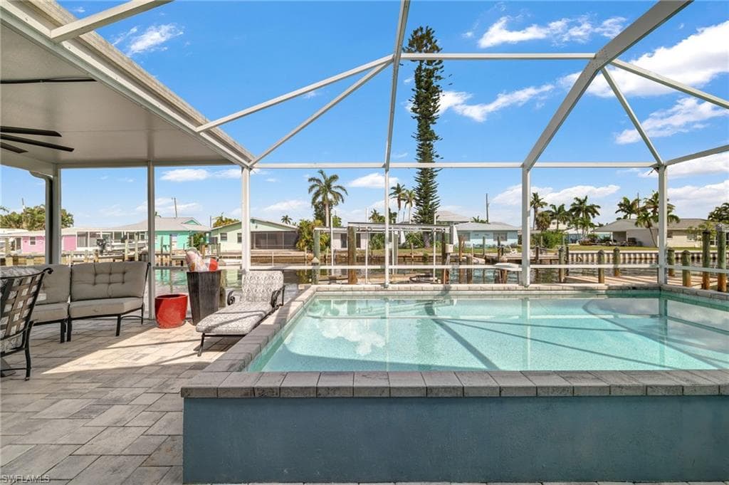 Screened lanai featuring a swimming pool, integrated spa, and paver decking