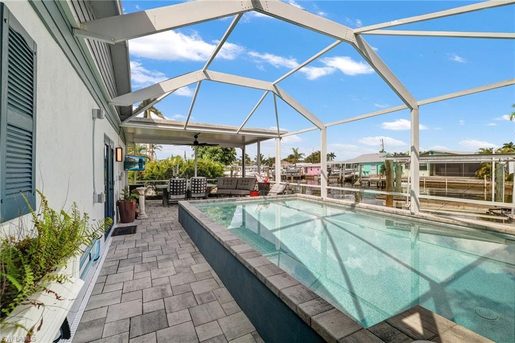 Screened lanai featuring a built-in swimming pool, paver patio, and covered outdoor living area
