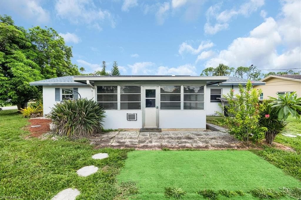 Rear exterior with a screened patio, stone paver patio, and grass lawn