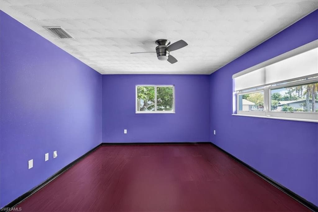 Ceiling fan with light fixture, multiple windows for natural light, and wood-finish flooring