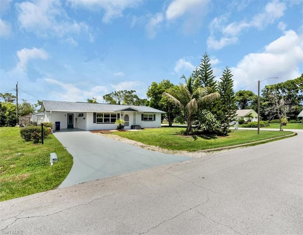 Single-story residence featuring a white exterior, attached carport, and a paved driveway