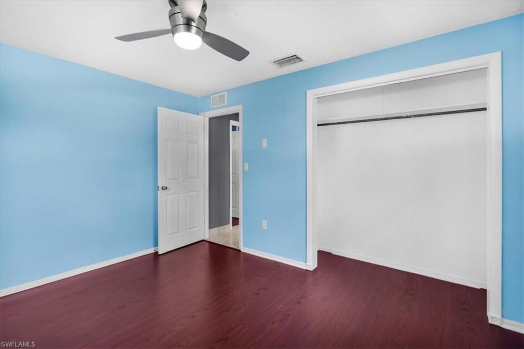 Wood-finish flooring, ceiling fan with integrated lighting, solid core door, and built-in closet with hanging rod
