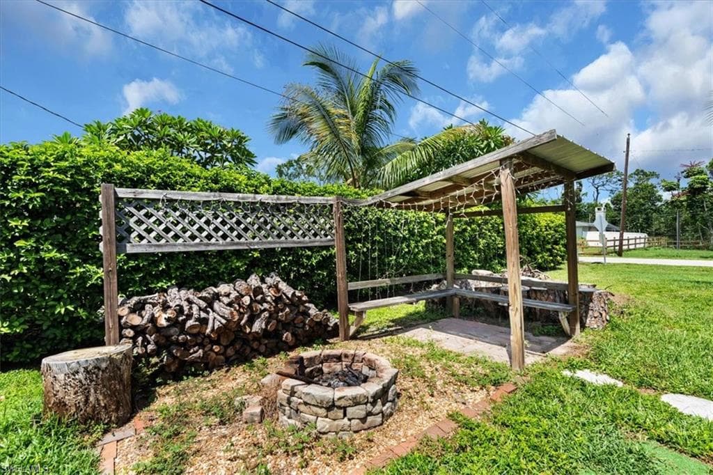Outdoor gathering area featuring a stone-lined fire pit, a wooden pergola with built-in bench seating, and a lattice privacy screen