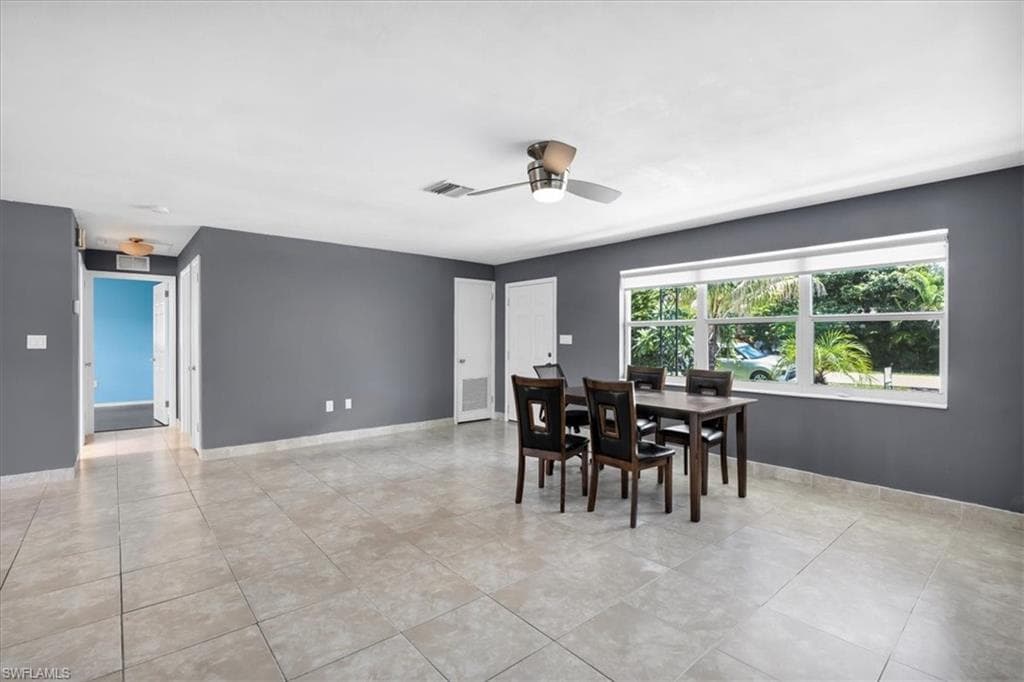 Expansive tiled flooring throughout, large windows with natural light, modern ceiling fan with integrated lighting, and multiple entryways