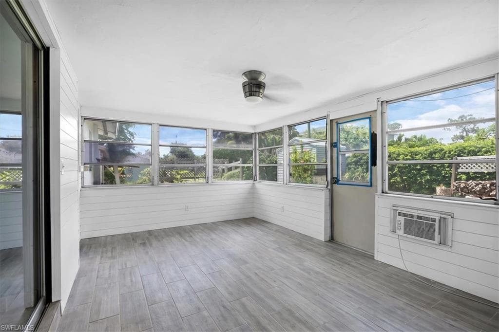 Screened room featuring wood-finish flooring, white horizontal paneling, and multiple windows
