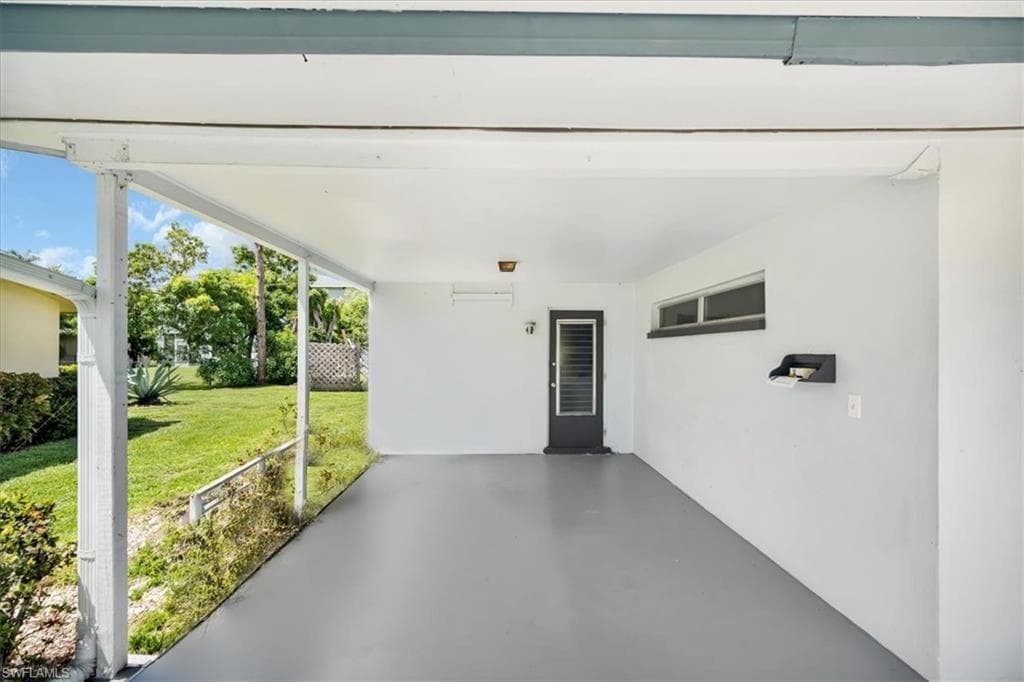 Covered patio with a concrete floor, exterior door with louvered inserts, and a horizontal window