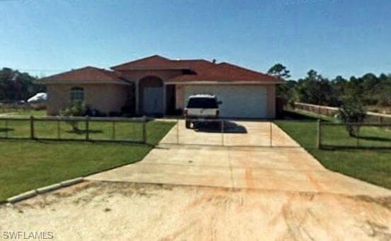 Stucco exterior with a tile roof, an arched entry, an attached garage, and a fenced yard