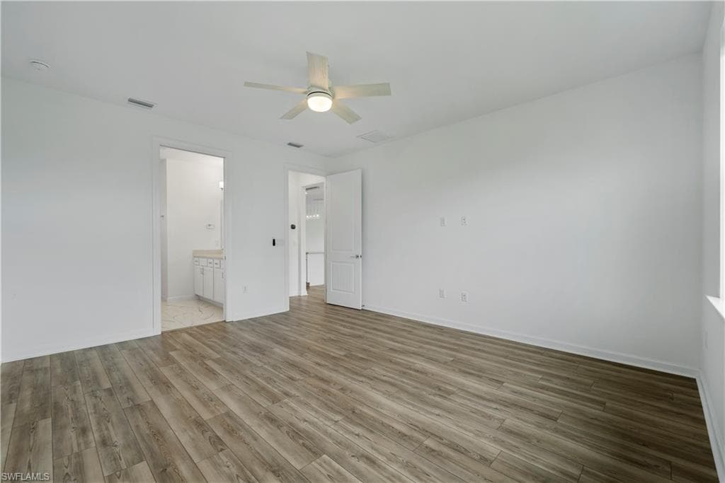 Wood-finish flooring, white walls, and a ceiling fan with integrated lighting