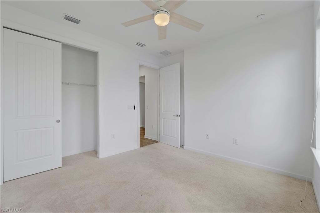 Wall-to-wall carpeting, ceiling fan with integrated lighting, paneled interior doors, and a built-in closet system