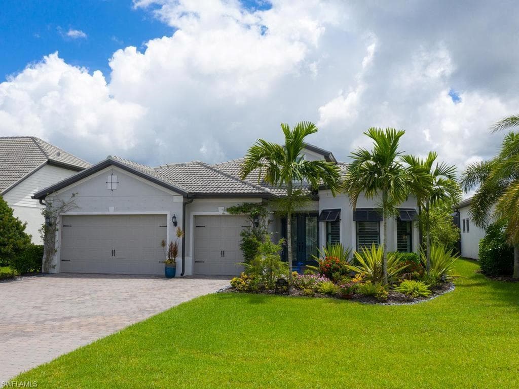 Stucco exterior with a tiled roof, 3-car garage, and a paver driveway