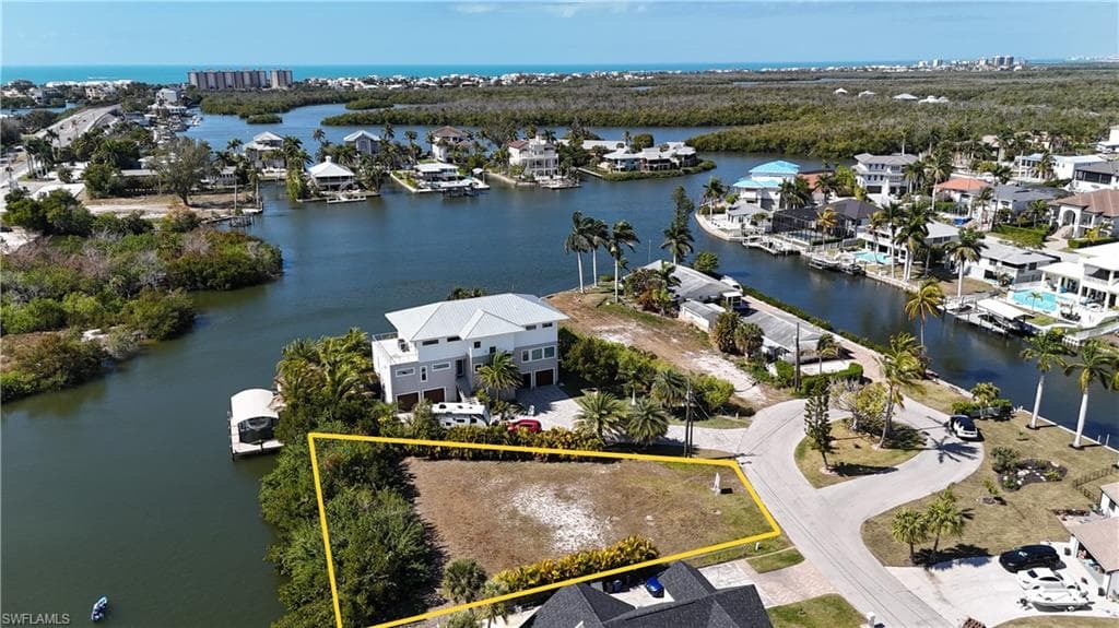 Aerial perspective of suburban area featuring a large body of water and property boundaries highlighted