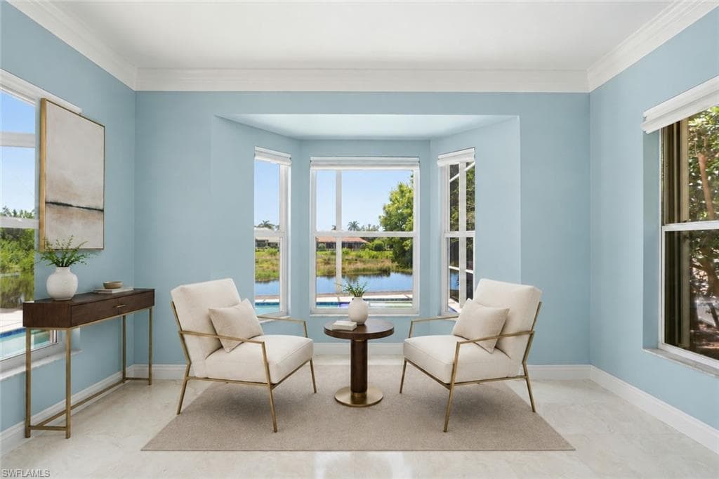 A light-filled sitting room surrounded by oversized windows with tranquil pool and water views.