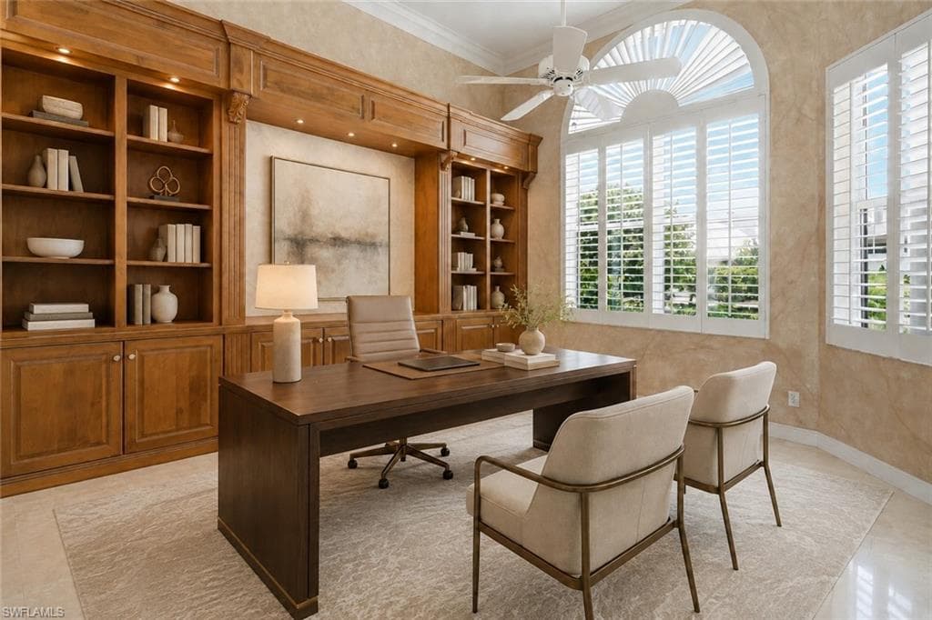 A distinguished home office featuring extensive custom wood cabinetry, illuminated shelving, and generous workspace.