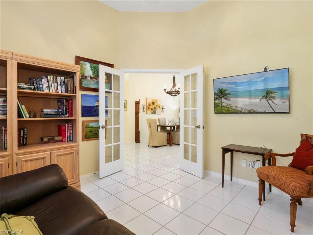 White square tile flooring, built-in wood-finish shelving, and white French doors